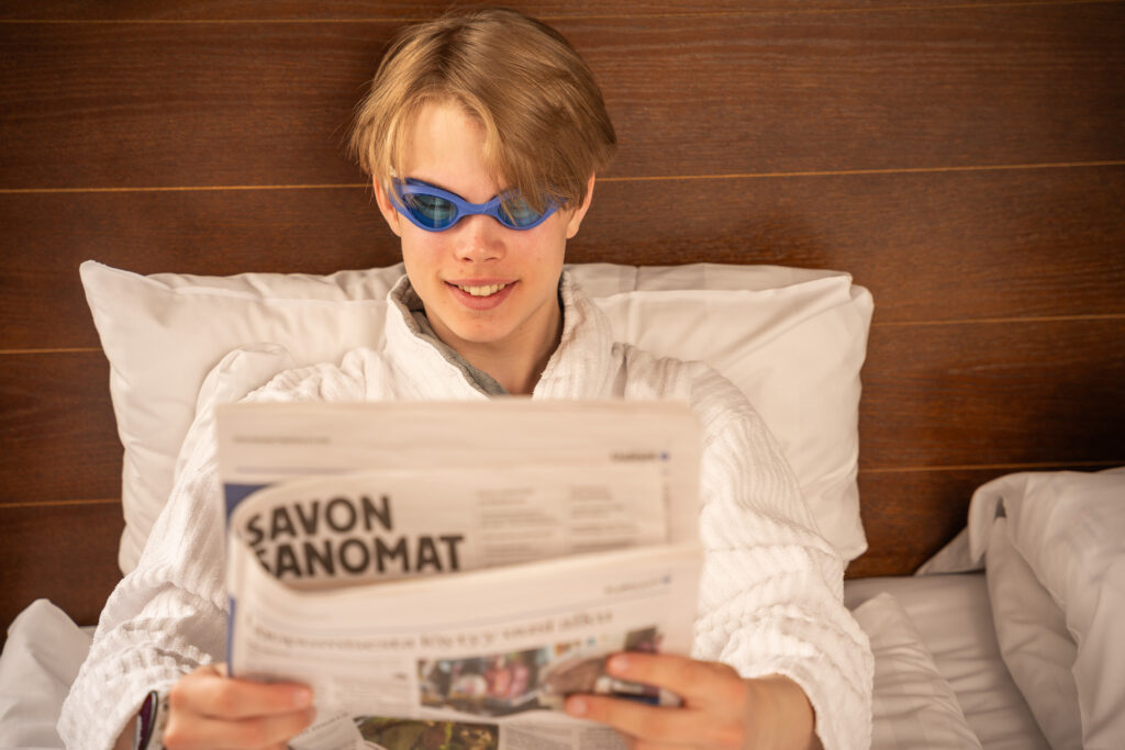 Ihminen lukemassa lehteä sängyllä